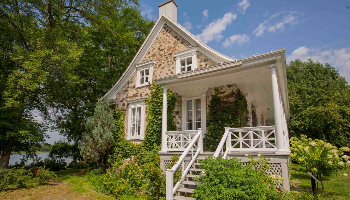 Maison d'inspiration française avec un porche et des marches blanches.