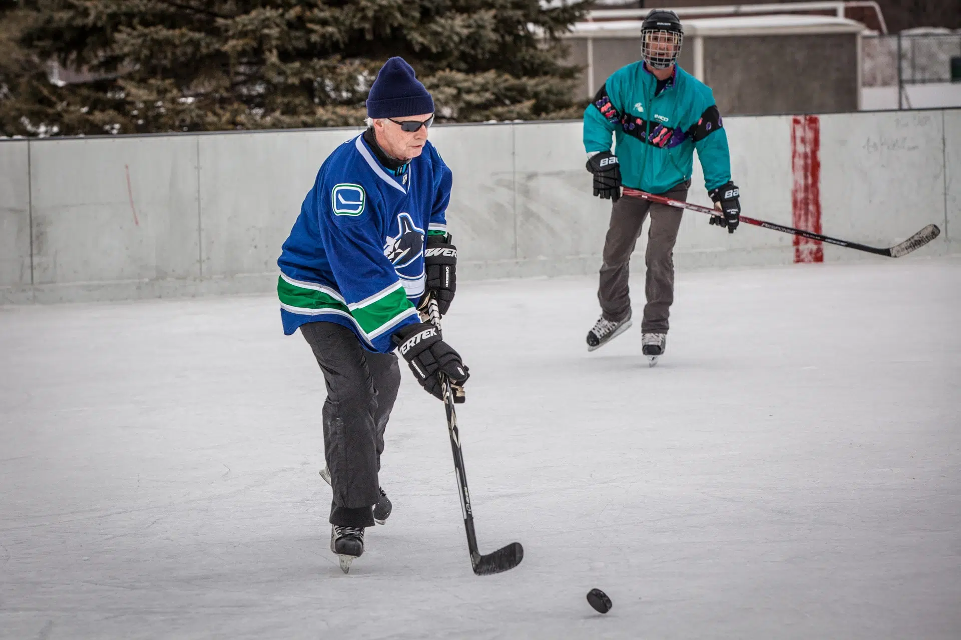 Personnes âgées pratiquant le hockey sur une glace extérieure en hiver