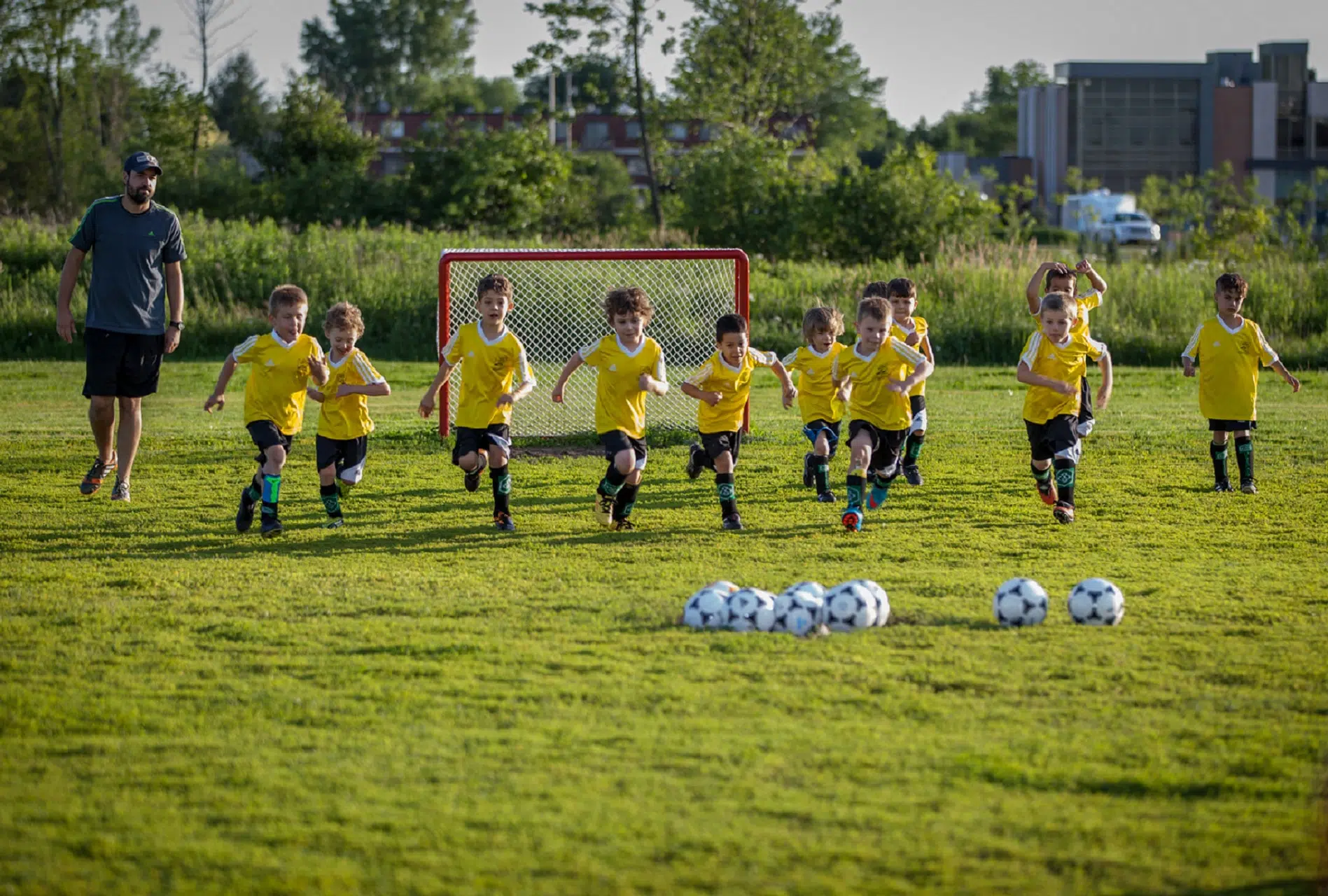 groupe d'enfant pratiquant le soccer sous l'œil d'un entraineur