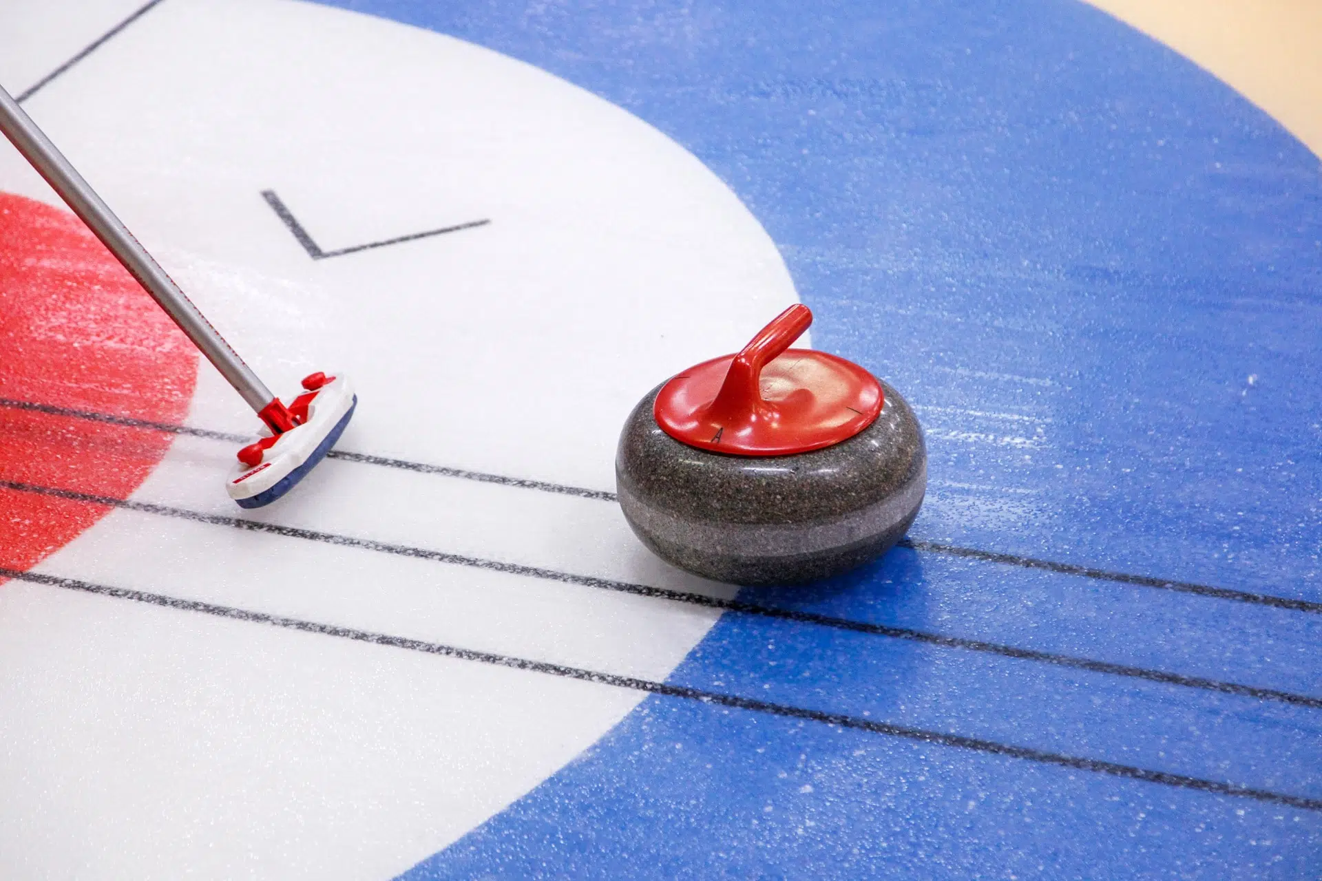 vue d'un balais et d'une pierre de curling sur la glace