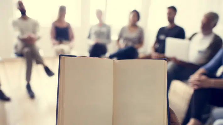 Atelier de lecture avec plusieurs personnes assis en rond et tenant des livres dans leurs mains.