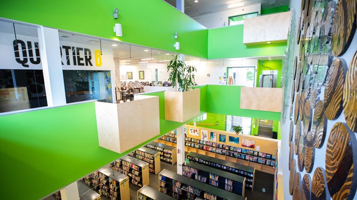 Vue en plongée de la bibliothèque, de son local Quartier B et de ses rayons de livres.