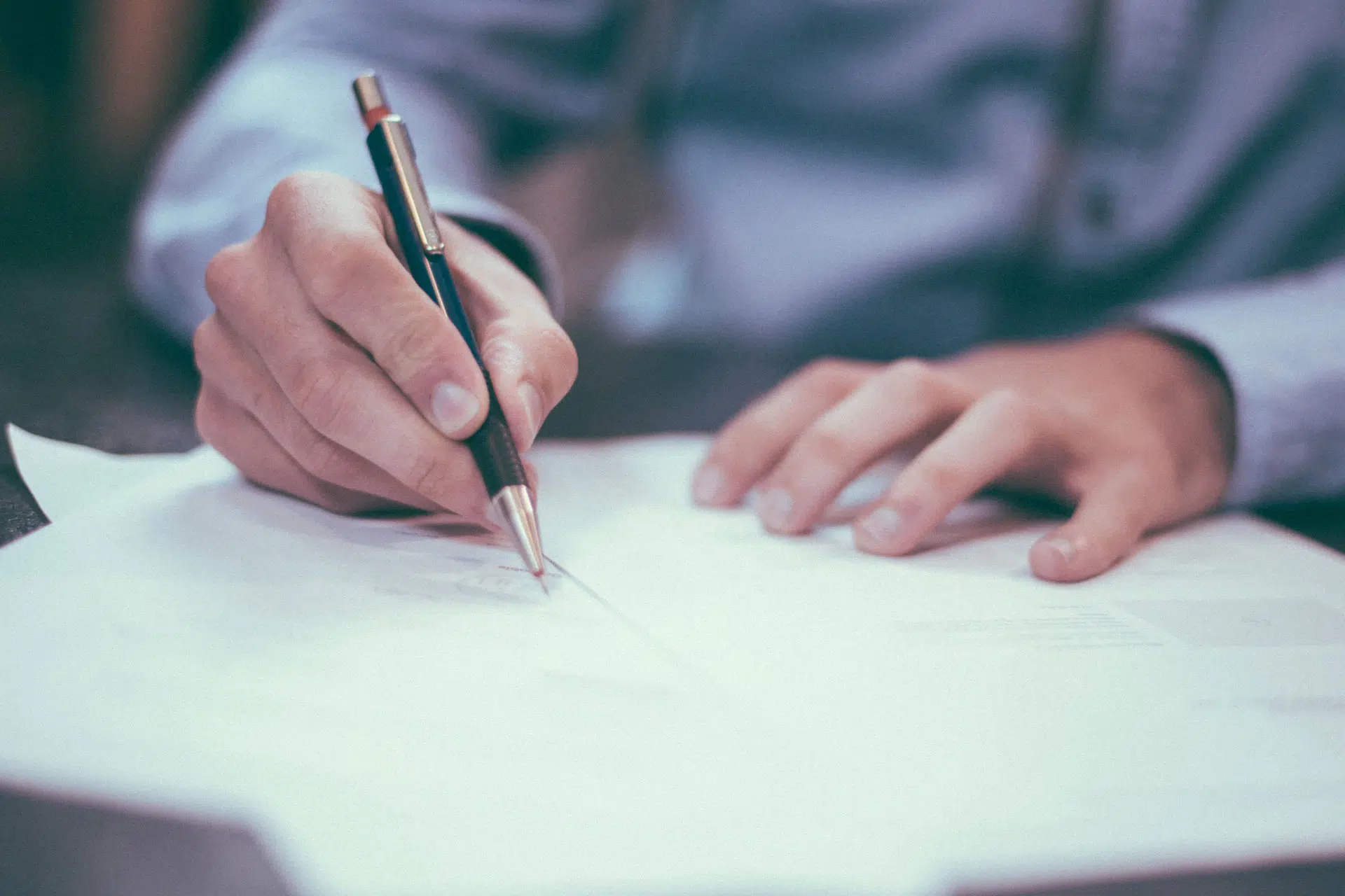 Gros plan sur les mains d'une personne qui tient un crayon et écrit sur une feuille.