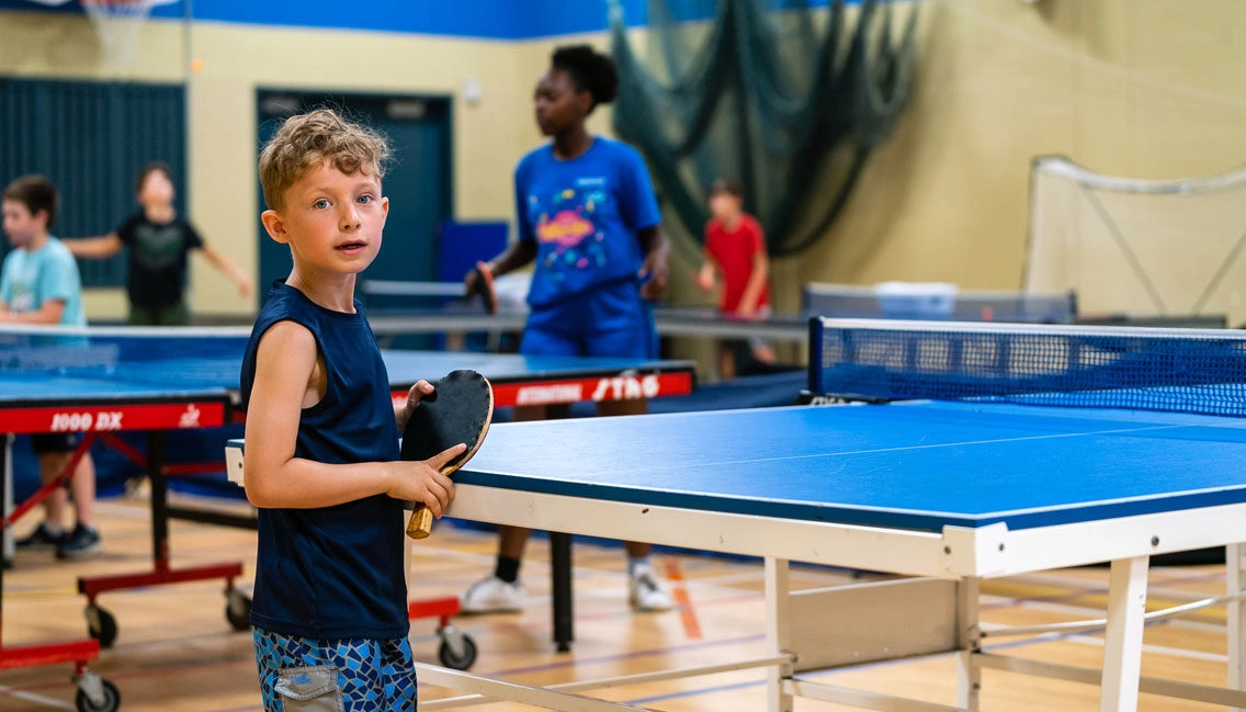 Une monitrice et des jeunes jouent au ping pong