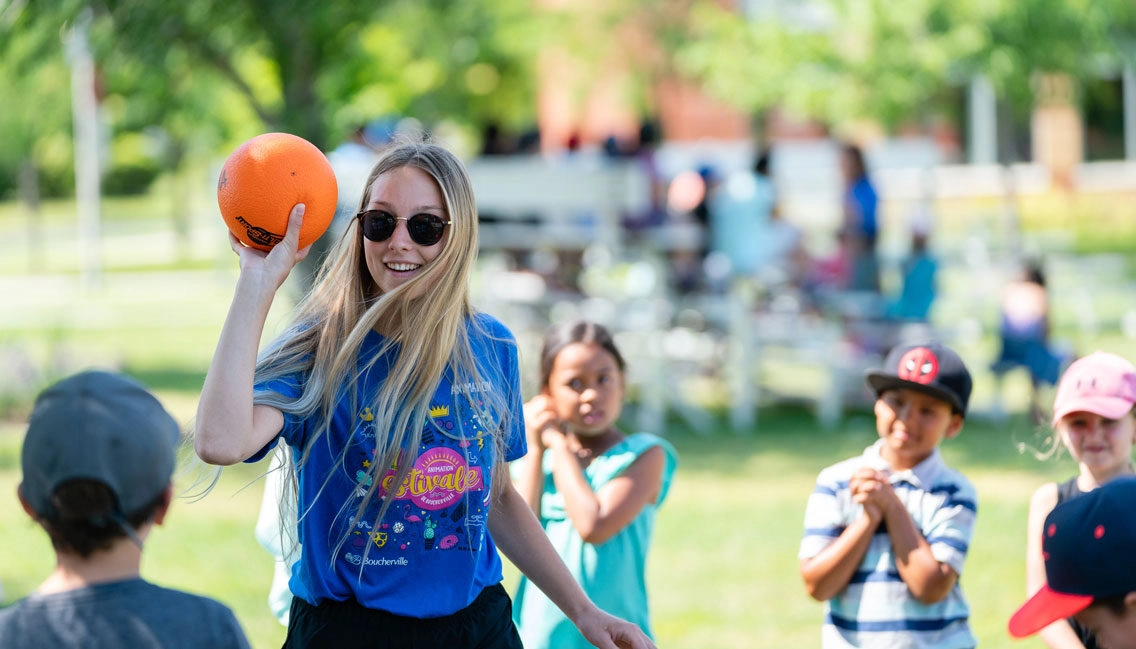 Une monitrice lance un ballon aux enfants - animation estivale