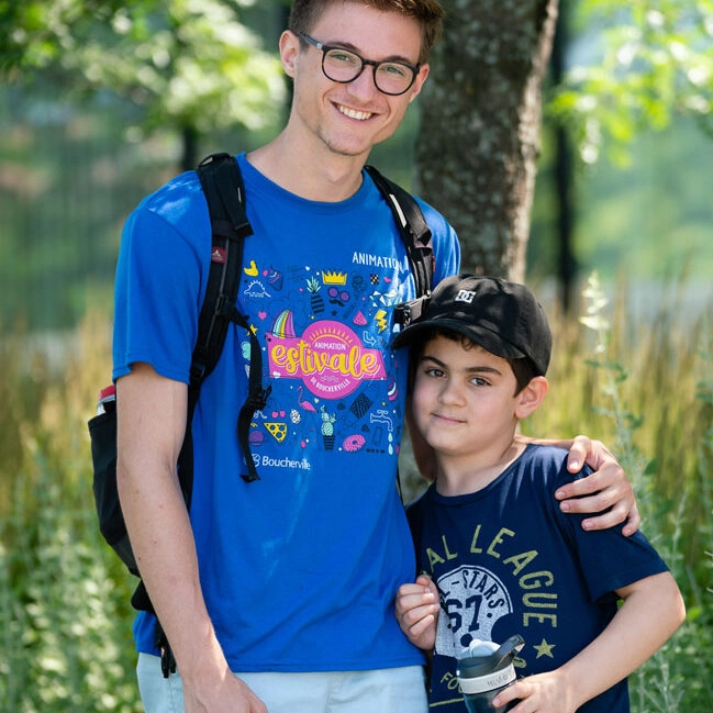 Un moniteur fait une accolade à un jeune garçon à l'animation estivale
