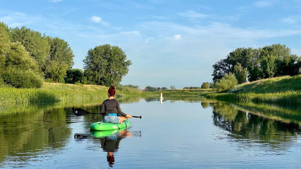 Une femme est assise sur une planche à pagaie sur le fleuve.