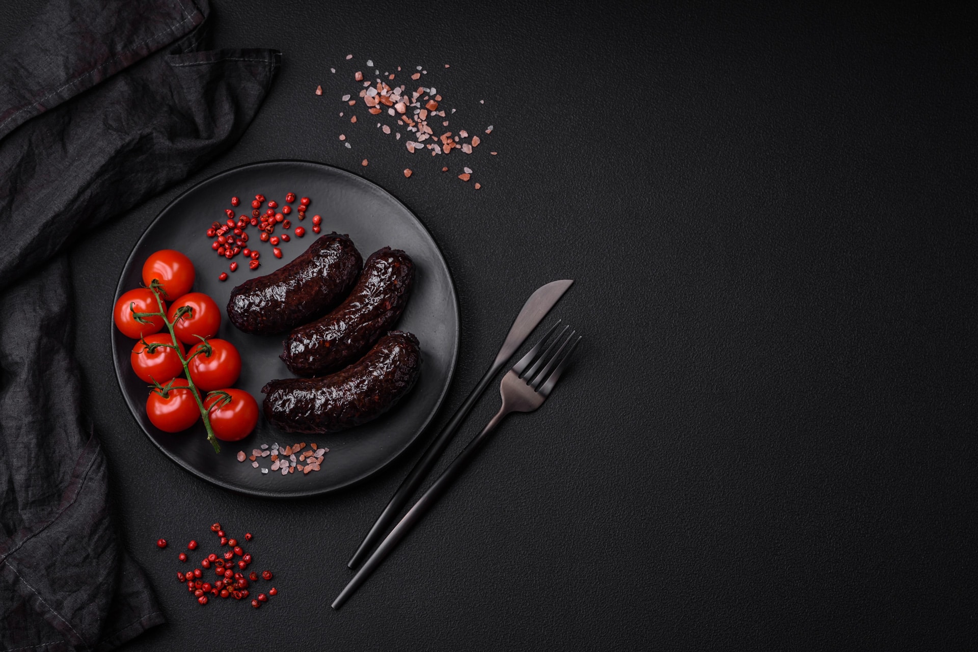 Plat de boudin avec des tomates cerises sur fond noir