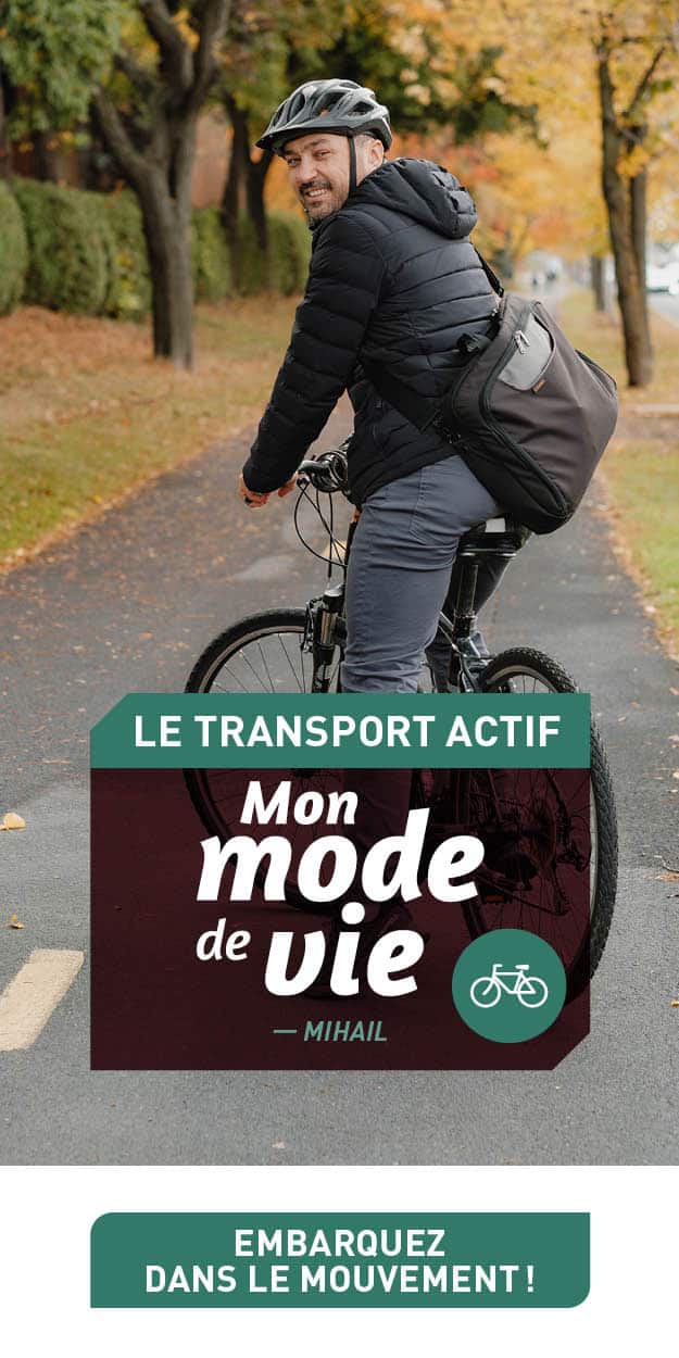 On voit un jeune homme se rendre au travail à vélo. Il est souriant.